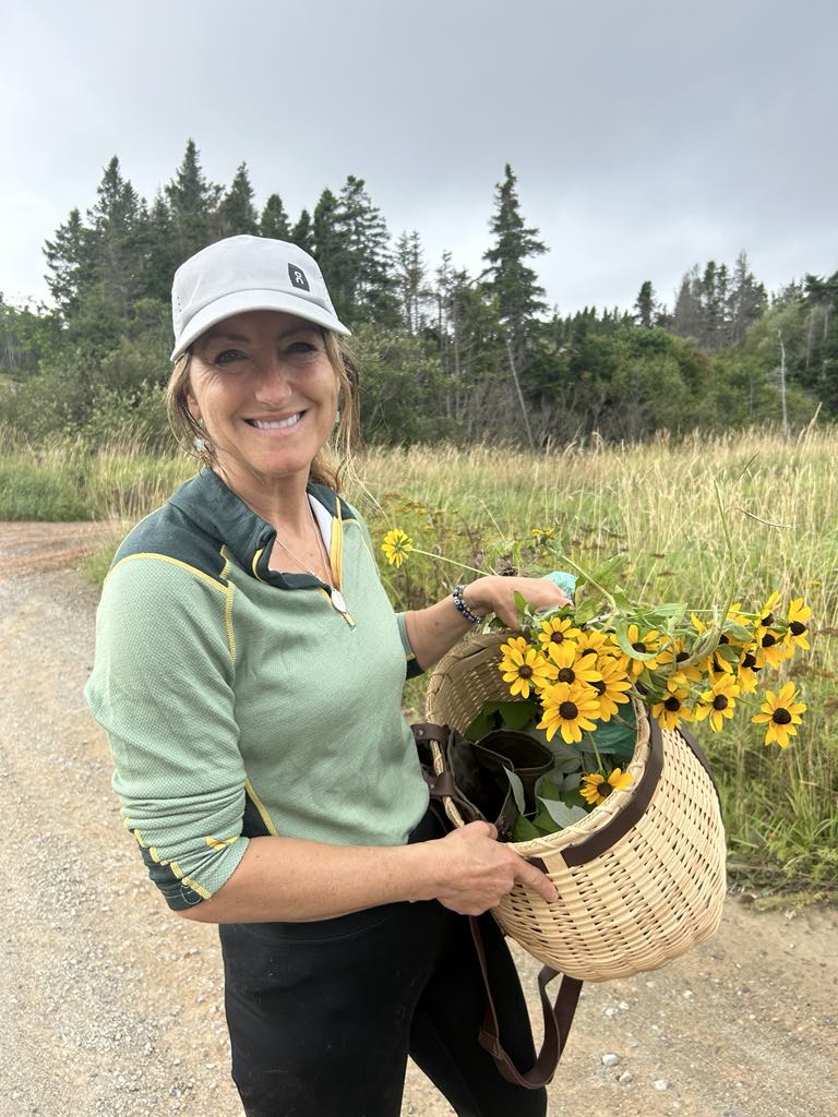 Une femme se tient debout avec un panier rempli de fleurs jaunes